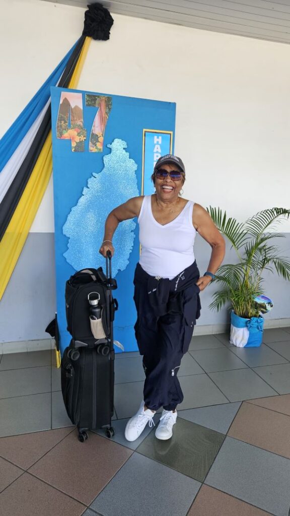 Woman traveler smiling with carry-on luggage at the airport, dressed comfortably and ready for a long flight
